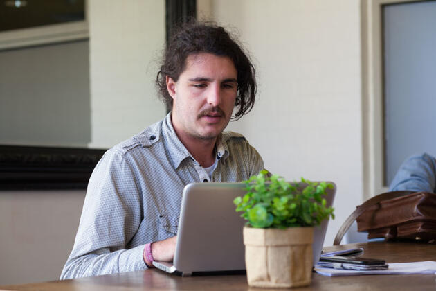 Man at home pensively using laptop computer.