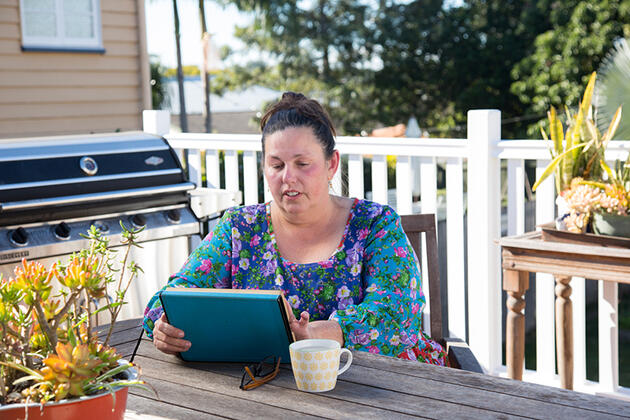 Woman sitting outside her home with tablet computer.