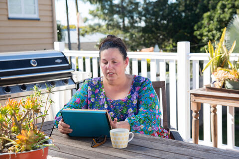 Woman sitting outside her home with tablet computer.